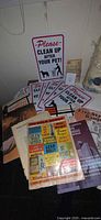 Overall lot showing stack of songbooks and multiple pet cleanup signs