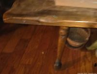 Close-up of tabletop edge and turned leg showing wood grain and wear