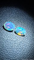 Pair of oval faceted Ethiopian opals on dark background showing color play