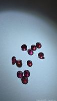 Group of loose round pink-red garnets on white surface