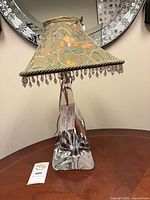 Full view of crystal lamp with embroidered beaded shade on wood surface