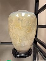 Full view of Armani ceramic vase on wood stand displaying glaze and form