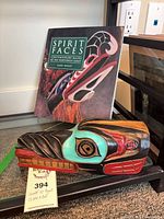 Front view of wooden wolf head carving and Spirit Faces book