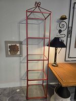 Full view of red metal shelving unit with glass shelves