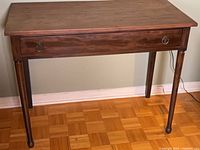 Front view of wooden writing desk showing drawer and legs