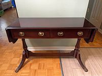 Front view showing drawers, drop-leaf sides down, pedestal base