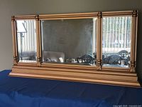 Front view showing three mirrored panels and gold frame