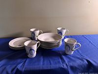 Overall view of stacked bowls, plates and four mugs showing leaf design