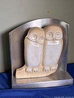 Front view showing two owl figures and metal backdrop