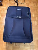 Front view of black Roots suitcase lying flat
