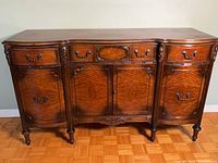 Front view of wooden buffet showing drawers, cabinet doors, brass pulls