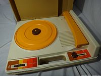 Top view of Fisher-Price model 825 turntable with lid open showing orange platter, tonearm, controls