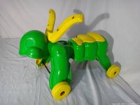 Left front view of green and yellow ride-on grasshopper toy