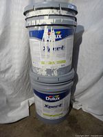 Two stacked Dulux X-Pert 5-gallon paint pails