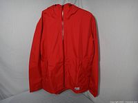 Front view of red MEC rain jacket hanging, shows overall condition and colour