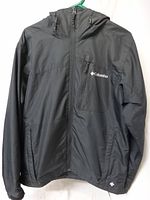 Front view of black Columbia windbreaker showing hood, full zipper, three exterior pockets, logo, size medium