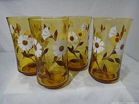 Front view of four amber daisy tumblers