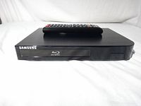 Front view of Samsung BD-F5100 Blu-ray player with remote on top