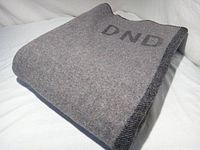 Folded grey wool blanket showing DND stencil and edge stitching