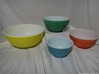 Four Pyrex bowls upright showing interior and exterior colour wear