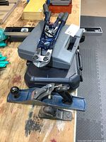 Stacked tools showing grey Dremel case, black case, bolt cutter, levels, hand planes