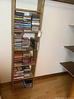 Tall narrow shelving unit filled with multiple shelves of CDs and some DVDs