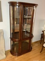 Full view of wood and glass curio cabinet, upper glass section and lower storage