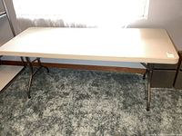 Full view of rectangular resin folding table on carpet
