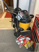 Full view of vacuum on cart with hose, wands, filter bag packs
