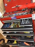 Open top of red toolbox showing assorted screwdrivers, pliers, sockets and ratchets