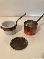 Both copper saucepans and lid displayed