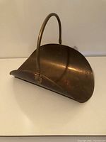 Full view of brass fireplace log holder, showing overall shape and handle