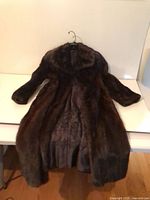 Full view of brown fur coat laid flat showing exterior, sleeves, collar and length