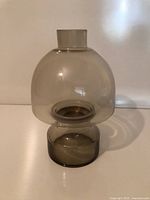 Front view of smoky grey glass hurricane candle holder showing dome, chimney and pedestal base