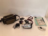Full lot view: camcorder, bag, accessories, manuals, cables, light meter