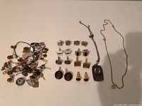 Full lot showing pile of pins/tacks, arranged cufflinks and two necklaces