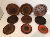 All nine carved wooden plates arranged to show variety of designs and finishes