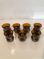 Seven amber glass tumblers arranged in row