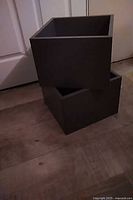 Two grey cubic boxes stacked on floor
