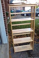 Front view of tall wooden bookcase showing four shelves and top