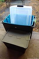 two stacked storage totes, one dark green with clear lid inside, one black with gray lid