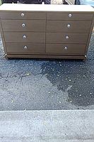 Front view of light wood veneer dresser showing eight drawers with chrome knobs