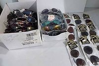 two boxes of loose sunglasses and packaged clip-ons