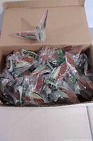 Open cardboard box showing large quantity of individually bagged bird magnets