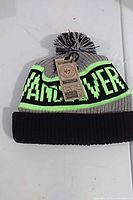 Full view of knit beanie showing grey body, black cuff, pom