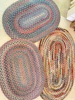 Three oval braided rugs laid out to show size and colour variations