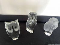 Front view of three glass owl figurines