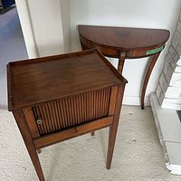 French walnut tambour door side table and mahogany demi-lune console table side by side