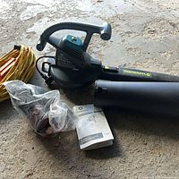 Yardworks blower/vac with nozzle, bag in plastic, manual and coiled yellow extension cord on floor