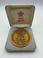 Medal obverse in case showing logo, rings, legend and date